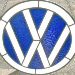 A blue and white stained glass volkswagen logo hanging on a wall.