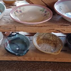 A wooden shelf with a variety of bowls on it.
